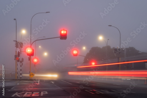Long exposure image of car and bus light trails at street intersection in a foggy morning, Auckland.