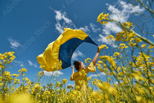 woman with the Ukrainian flag, waving ukrainian flag, woman with a flag of Ukraine in a yellow rapeseed field photo