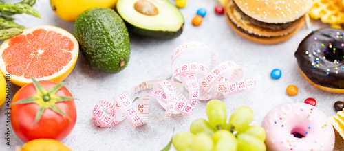 Flat lay of Healthy and unhealthy food from fruits and vegetables vs fast food, sweets and pastry on gray concrete background. Diet and detox against calorie and overweight lifestyle concept.