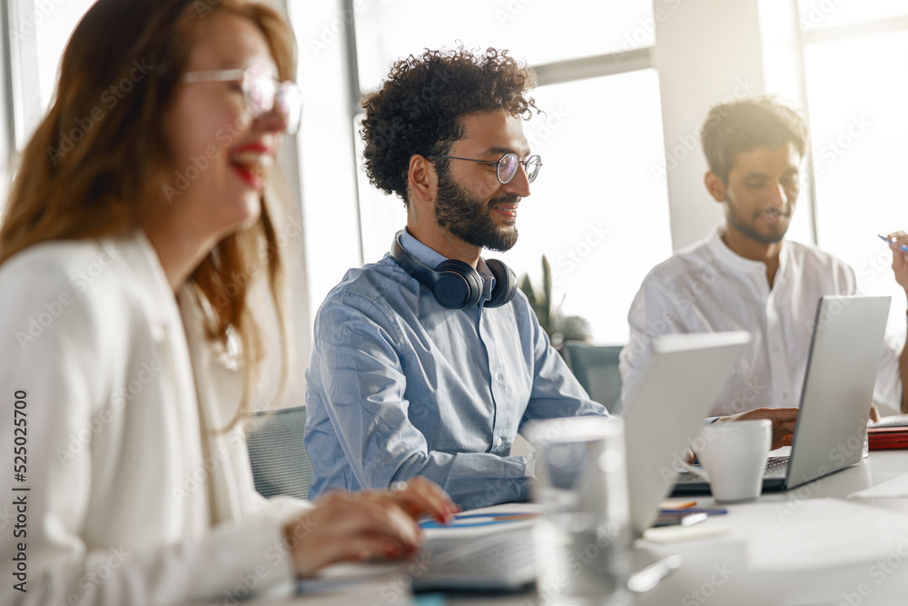 Fototapeta premium Group of young diverse coworkers analyzing sales report while working together in the office