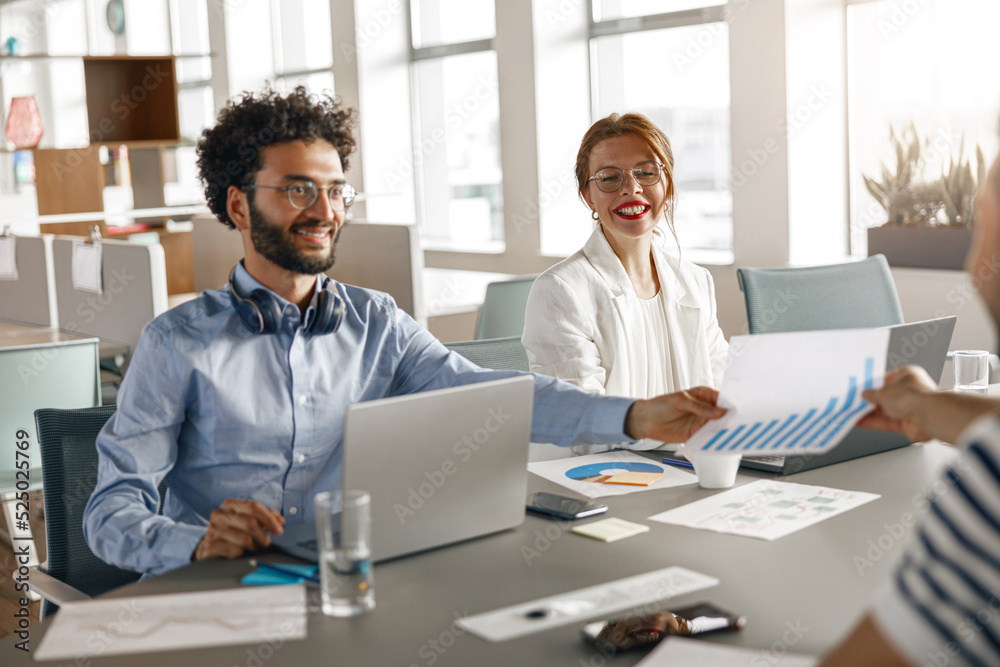 Group of happy diverse coworkers analyzing sales report while working together in the office Group of happy diverse coworkers analyzing sales report while working together in the office
