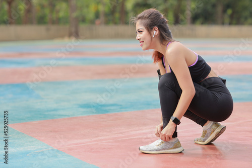 Portrait of beautiful asian woman in sportswear jogging outdoor with slim athletic legs. Sporty girl hands takes break and tying shoe. after workout. Healthy and lifestyle outdoor concept