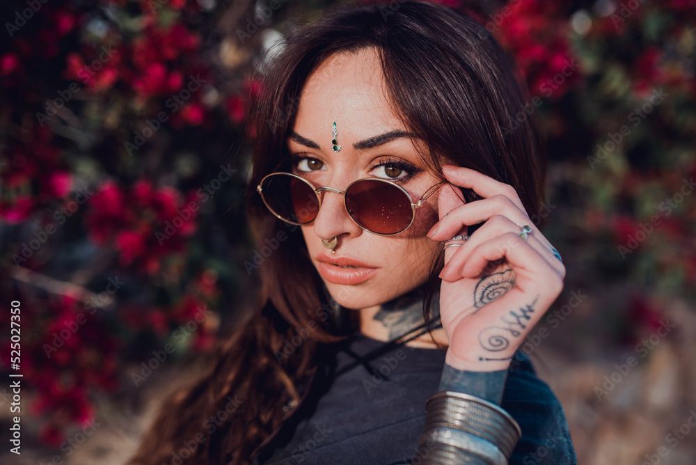 Woman in sunglasses against bush with colorful flowers in park Woman in sunglasses against bush with colorful flowers in park