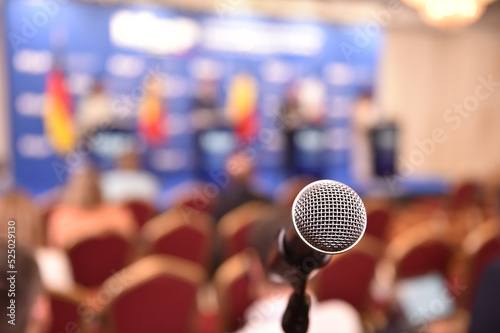 Detail shot with a microphone during a press conference. Audience in the background