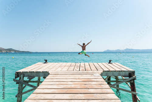 Excited boy jumping in sea from pier photo