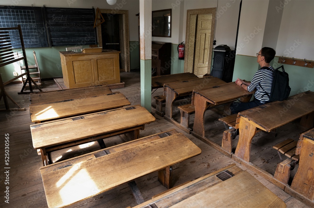 Als Erwachsener zu Besuch in einem historischen Klassenraum auf sehr engen und unbequemen Schulbänken Als Erwachsener zu Besuch in einem historischen Klassenraum auf sehr engen und unbequemen Schulbänken