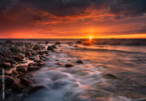 Morze bałtyckie - wschód słońca na plaży Gdynia Orłowo z widokiem na fale i kamieniste wybrzeże bałtyku, koło klifu w Orłowie