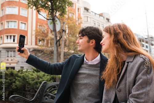 Cheerful romantic couple taking selfie on city street