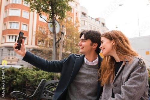Cheerful romantic couple taking selfie on city street