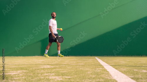 Padel player with black racket playing a match in the open behind the net court © REC Stock Footage