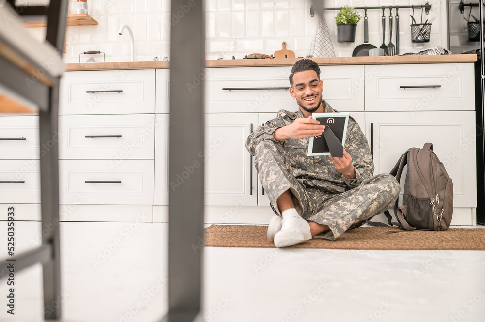Joyous young soldier gazing at the framed photograph Joyous young soldier gazing at the framed photograph