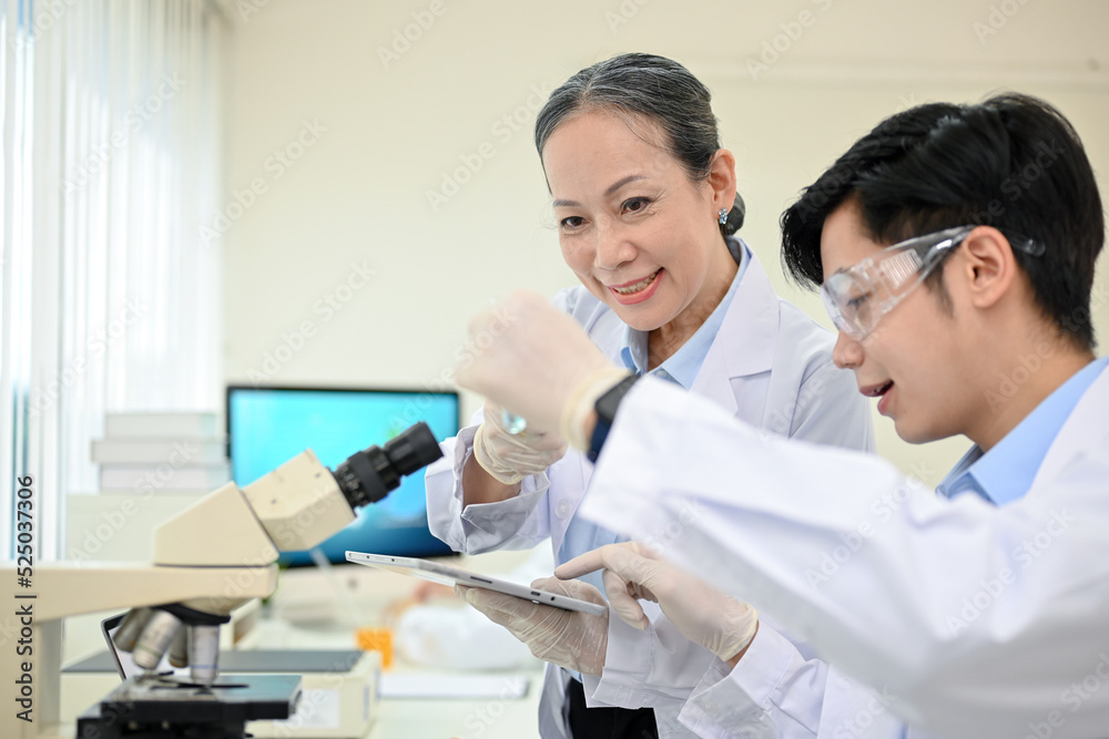 A talented Asian male medical specialist or scientist working in the lab with senior supervisor. A talented Asian male medical specialist or scientist working in the lab with senior supervisor.