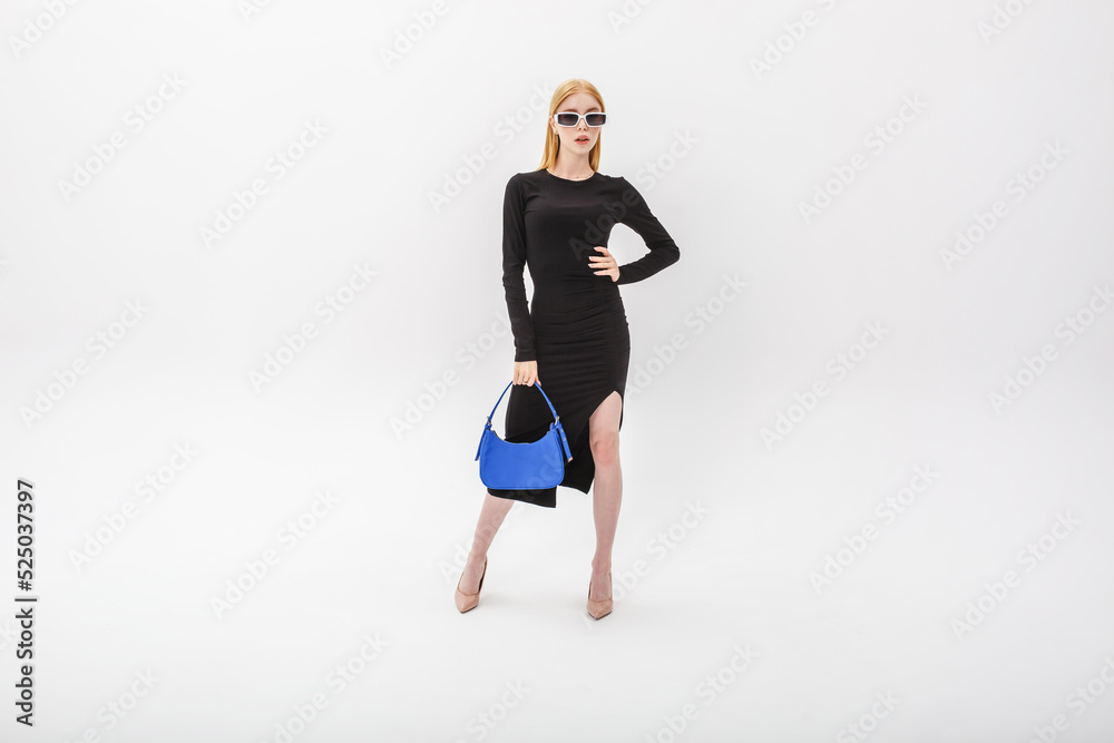 girl model in a black tight-fitting dress in white sunglasses and a blue handbag on a white background