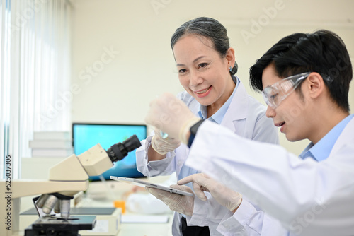 A talented Asian male medical specialist or scientist working in the lab with senior supervisor.