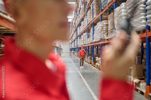 Two warehouse workers communicating over two-way radio