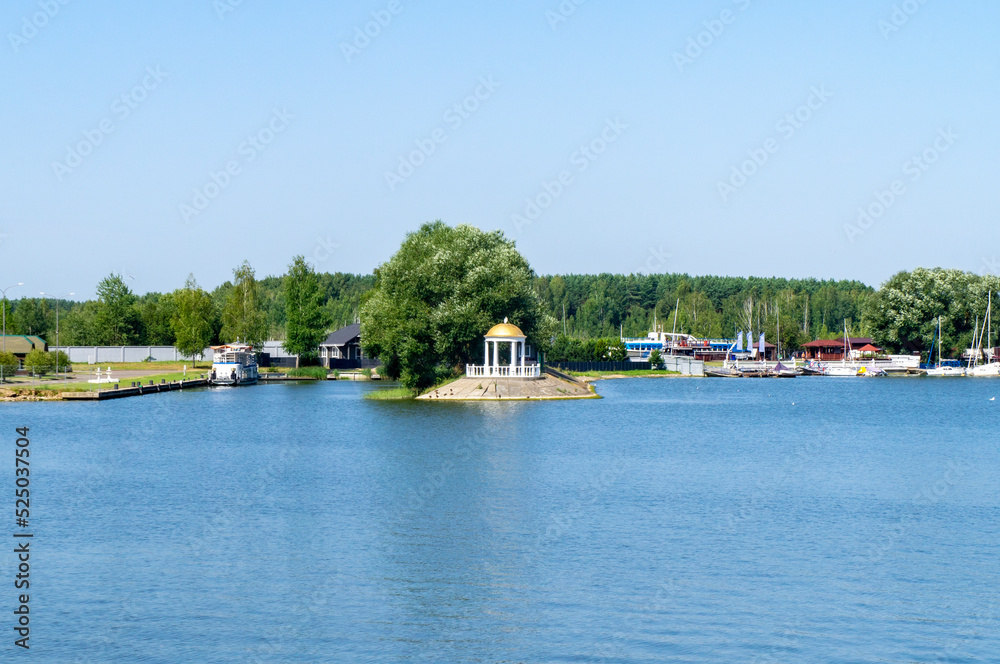 Obraz premium Lake view of the gazebo near the shore trees with a golden roof