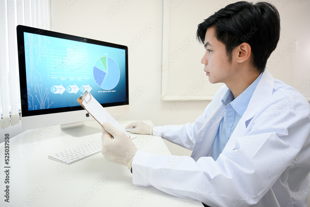 Handsome and smart Asian male doctor in white gown working at his office desk. Handsome and smart Asian male doctor in white gown working at his office desk.