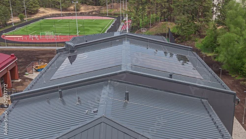 New school construction with solar panels installed over the gymnasium sports center - time lapse of sunshine, shadow and workers on the roof  photo