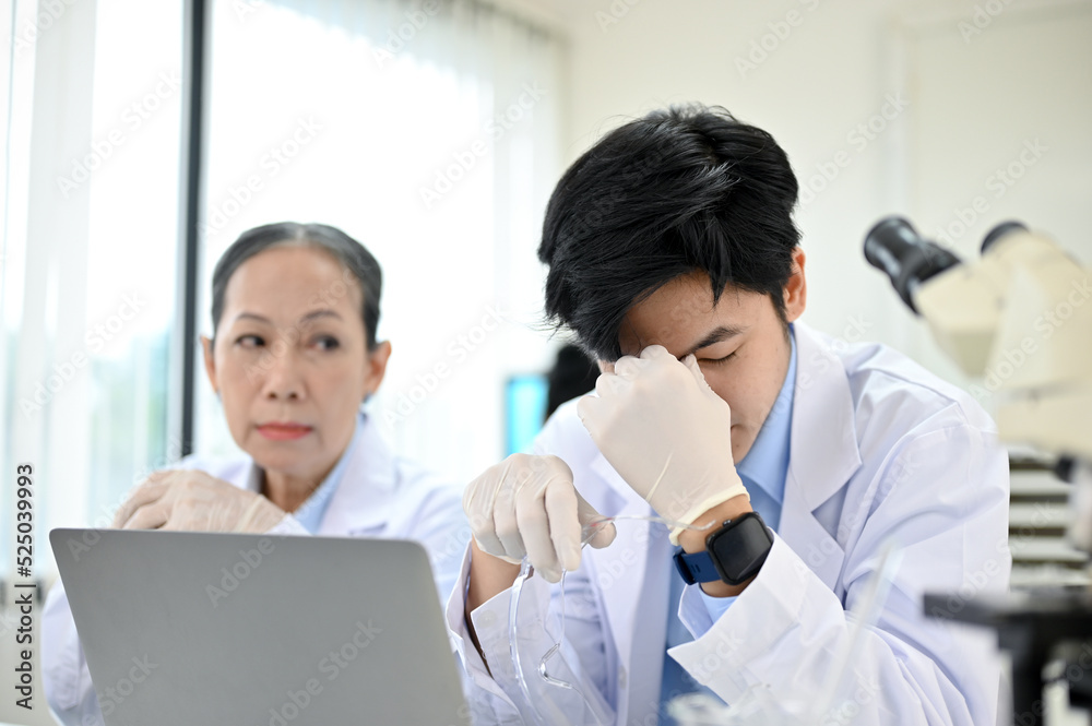 Stressed Asian male scientist upset with his experiment project while working in the lab Stressed Asian male scientist upset with his experiment project while working in the lab