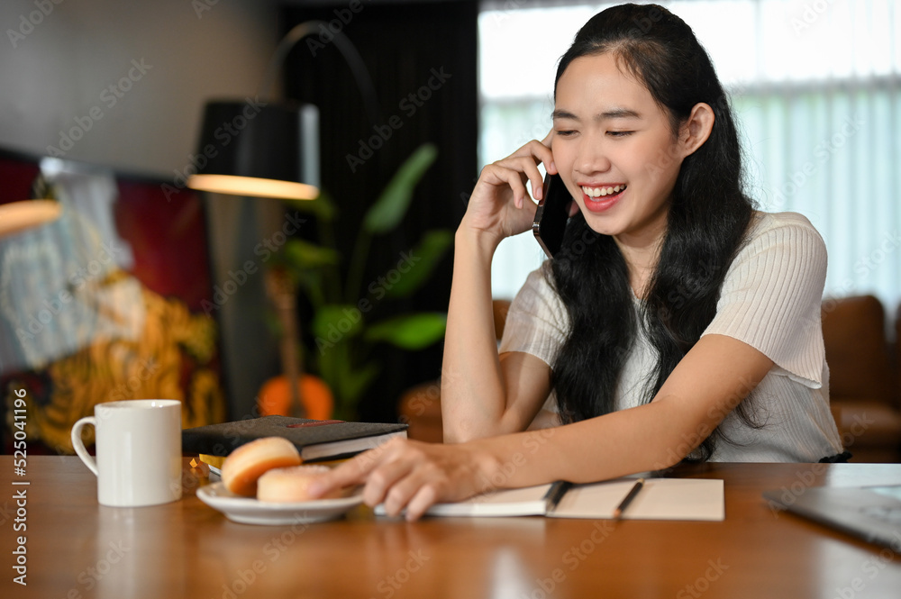Cheerful Asian female college student enjoys talking on the phone with someone Cheerful Asian female college student enjoys talking on the phone with someone