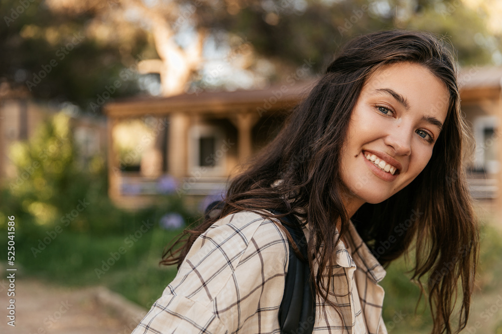 Close-up of beautiful young caucasian woman with snow-white smile looks at camera on street. Brunette woman wears casual shirt in spring. Leisure concept Close-up of beautiful young caucasian woman with snow-white smile looks at camera on street. Brunette woman wears casual shirt in spring. Leisure concept