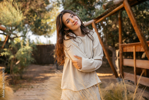 Εκτύπωση καμβά Cute young caucasian girl hugs herself with her arms, looks at camera relaxing outside city