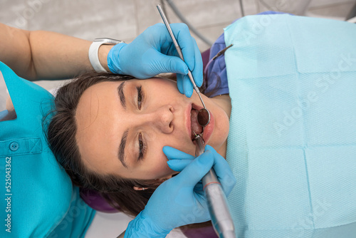 photo of a pretty woman being examined by a dentist with dental instruments in a dental chair.
