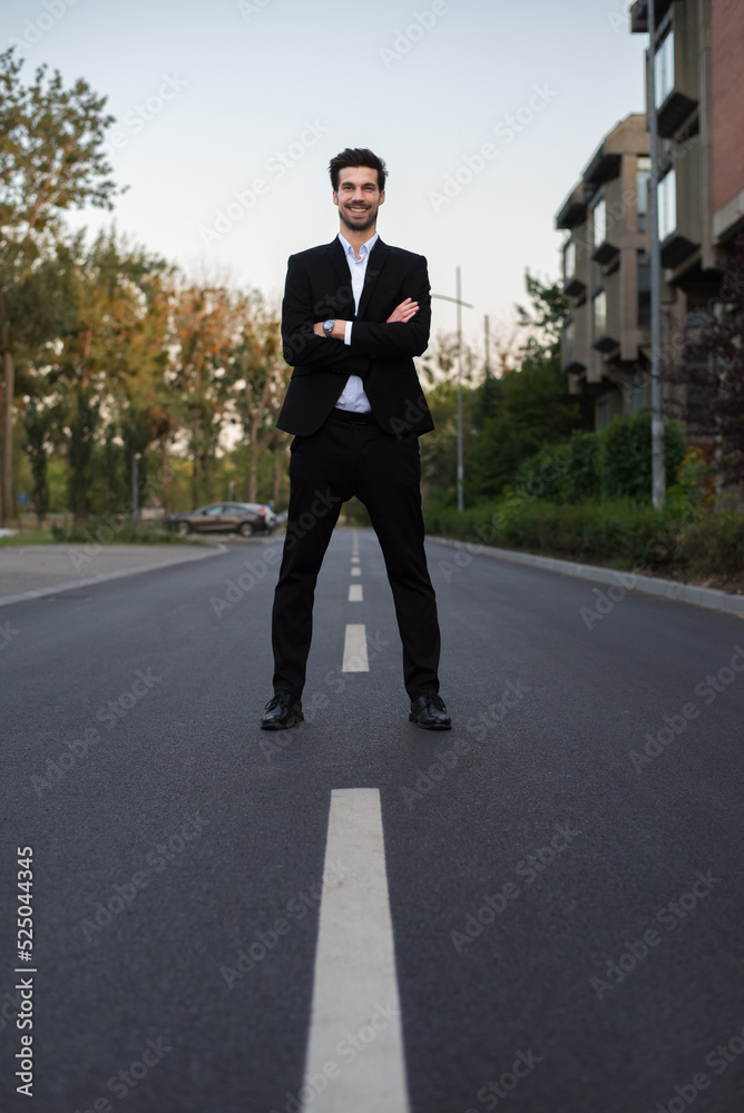 Young smiling businessman standing in the middle of the road Young smiling businessman standing in the middle of the road