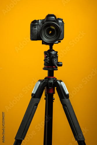 Dslr camera on tripod isolated with yellow background