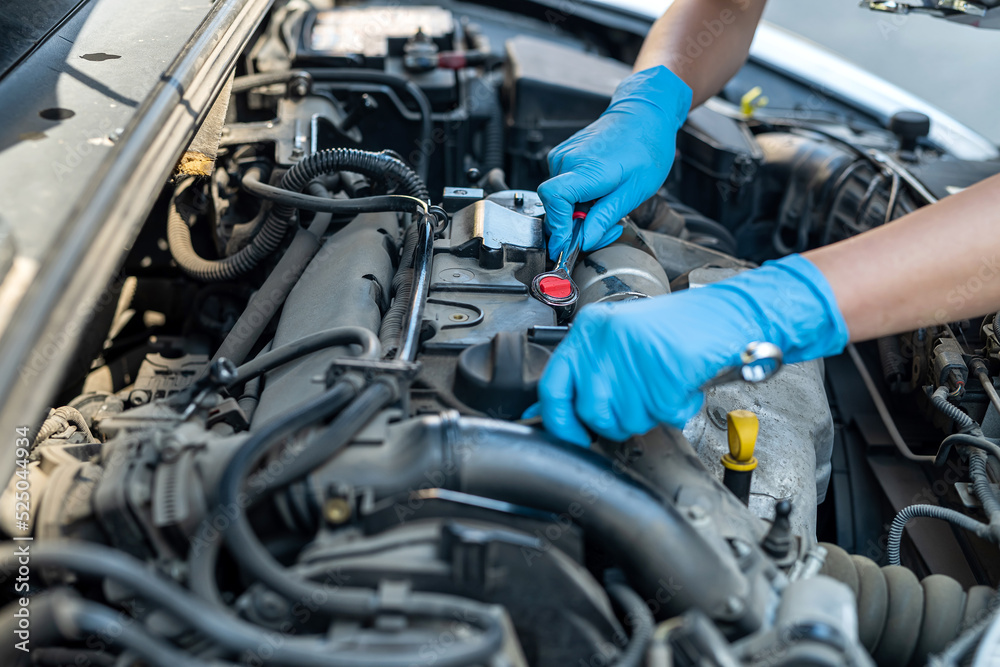 Fototapeta premium woman who works as a mechanic in a car service repairing the chassis of a car using a wrench.