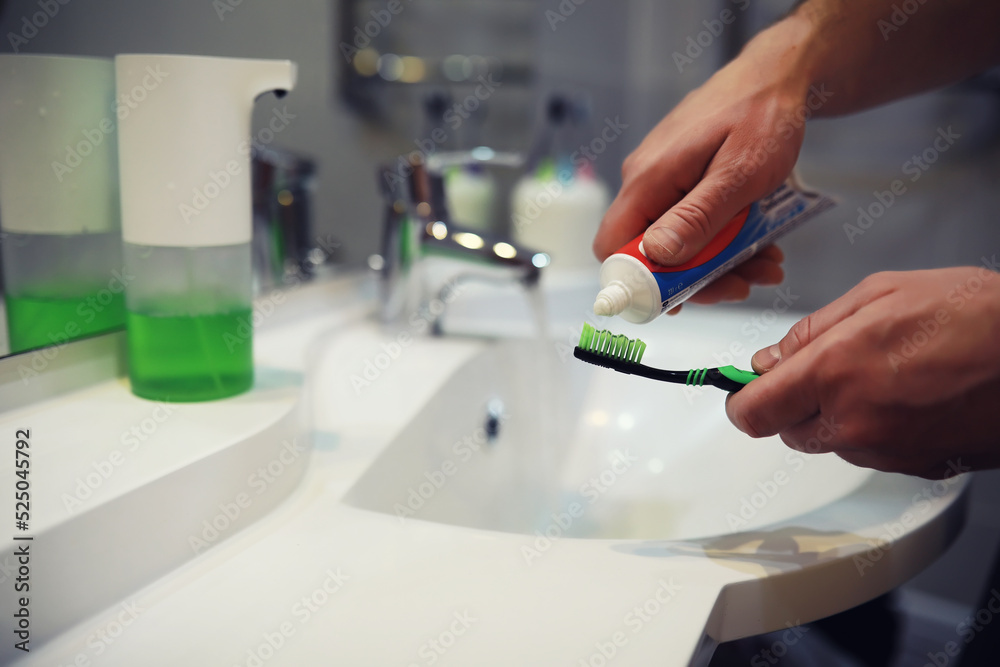 Hands with tooth brush and paste on blurred background in the bathroom in the sink. Selective focus. Hands with tooth brush and paste on blurred background in the bathroom in the sink. Selective focus.