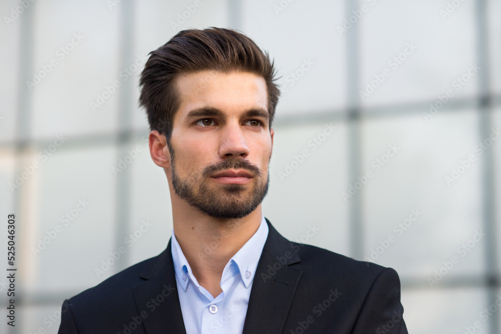 Young businessman standing in front of corporate office building Young businessman standing in front of corporate office building