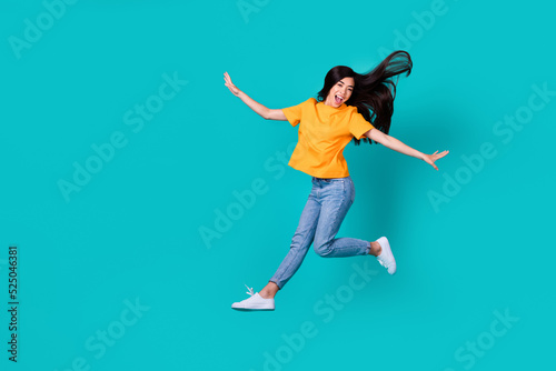 Full length photo of impressed brunette lady fly wear orange t-shirt jeans sneakers isolated on teal color background