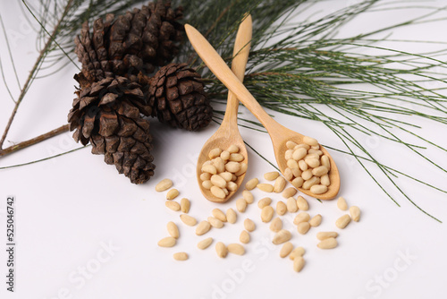 Heap of pine nuts and cedar cones on white background photo