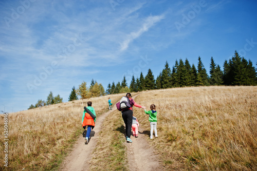 Woman is traveling with a childrens. Mom in the mountains. Climb to the top of the mountain with children. With the backpack climbed to the top.