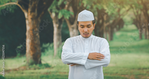 Religious muslim man traditional kandura praying outdoor at quiet nature environment sun beams.