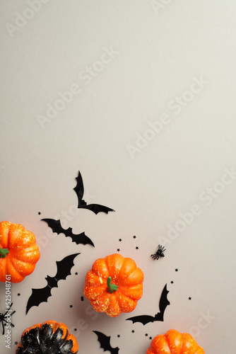 Halloween spooky decor concept. Top view photo of small pumpkins bat silhouettes spiders and confetti on isolated grey background with copyspace photo