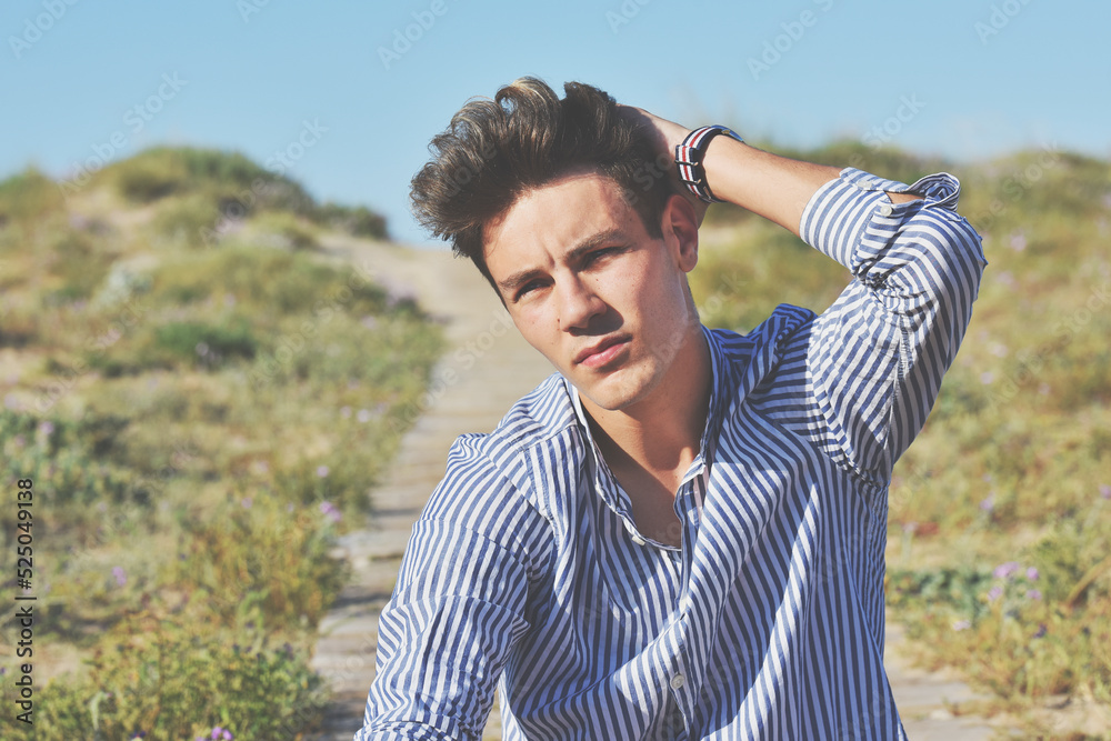 Guy posing on the beach alone, surrounded by Mediterranean vegetation and wooden walkway