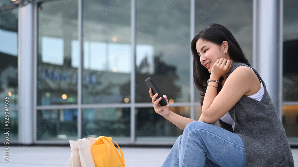 Stylish young asian woman sitting on the stairs outdoors and using smart phone Stylish young asian woman sitting on the stairs outdoors and using smart phone