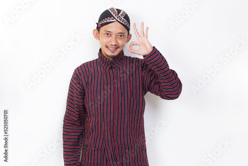 asian man with javanese traditional cloth lurik with ok sign gesture tumb up isolated on white background