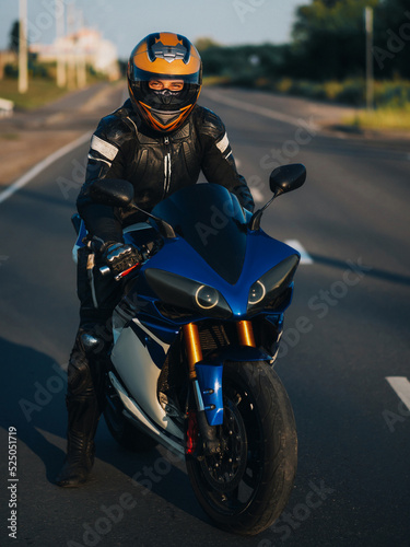 A motorcyclist on a sport bike on the road . Male biker in helmet and gear
