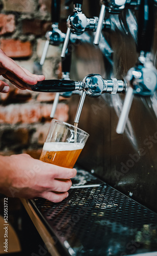 bartender hand at beer tap pouring a draught beer in glass serving in a bar or pub. tap room
