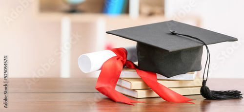 Graduation hat, diploma and books on table
