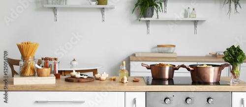 Modern electric stove with cookware and products in light kitchen