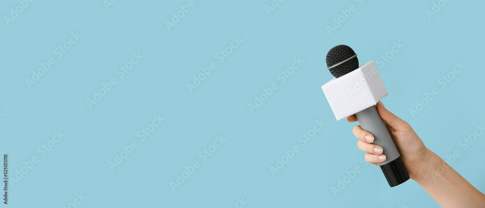 Journalist's hand with microphone on light blue background with space for text - obrazy, fototapety, plakaty 