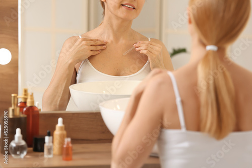 Mature woman using cosmetic...