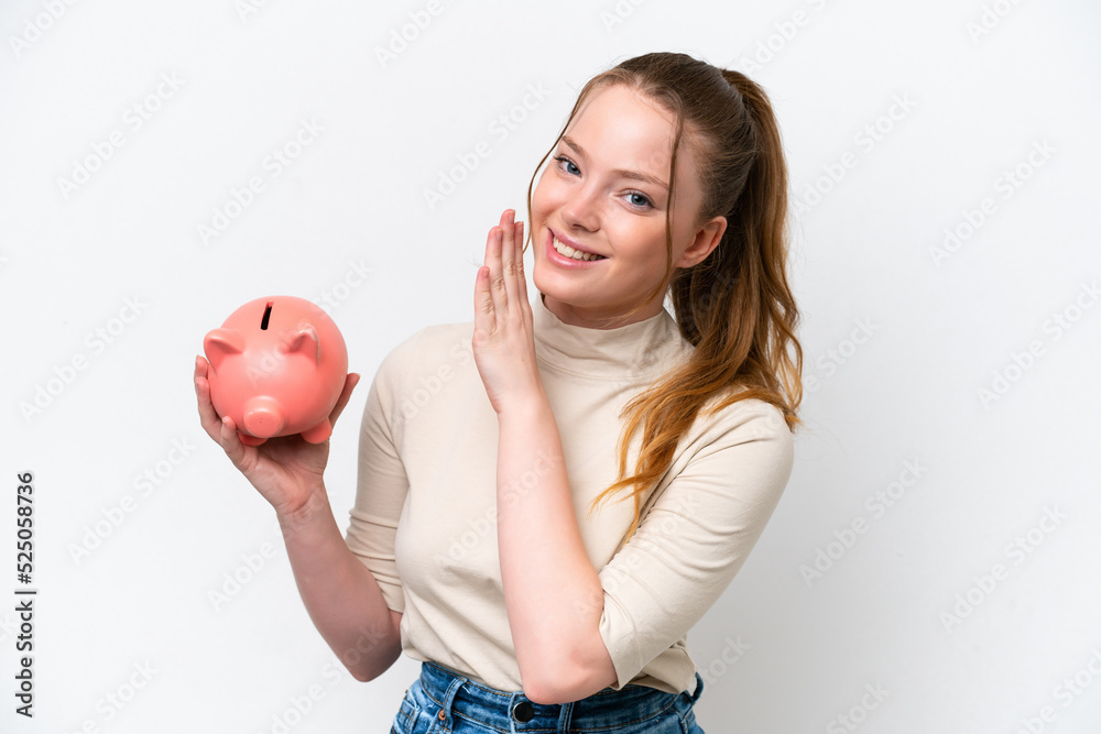 Young caucasian girl holding a piggybank isolated on white background whispering something Young caucasian girl holding a piggybank isolated on white background whispering something