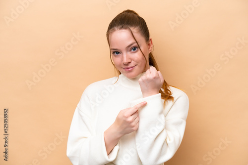 Young caucasian woman isolated on beige background making the gesture of being late © luismolinero