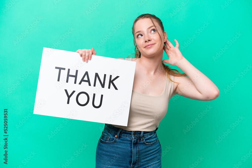 Young caucasian woman isolated on green background holding a placard with text THANK YOU and thinking