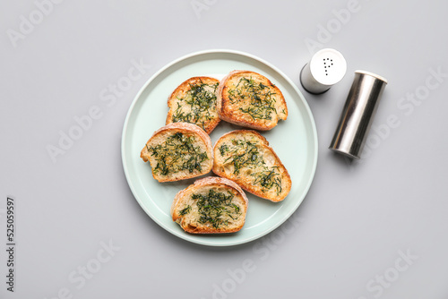 Plate with toasted garlic bread and spices on light background